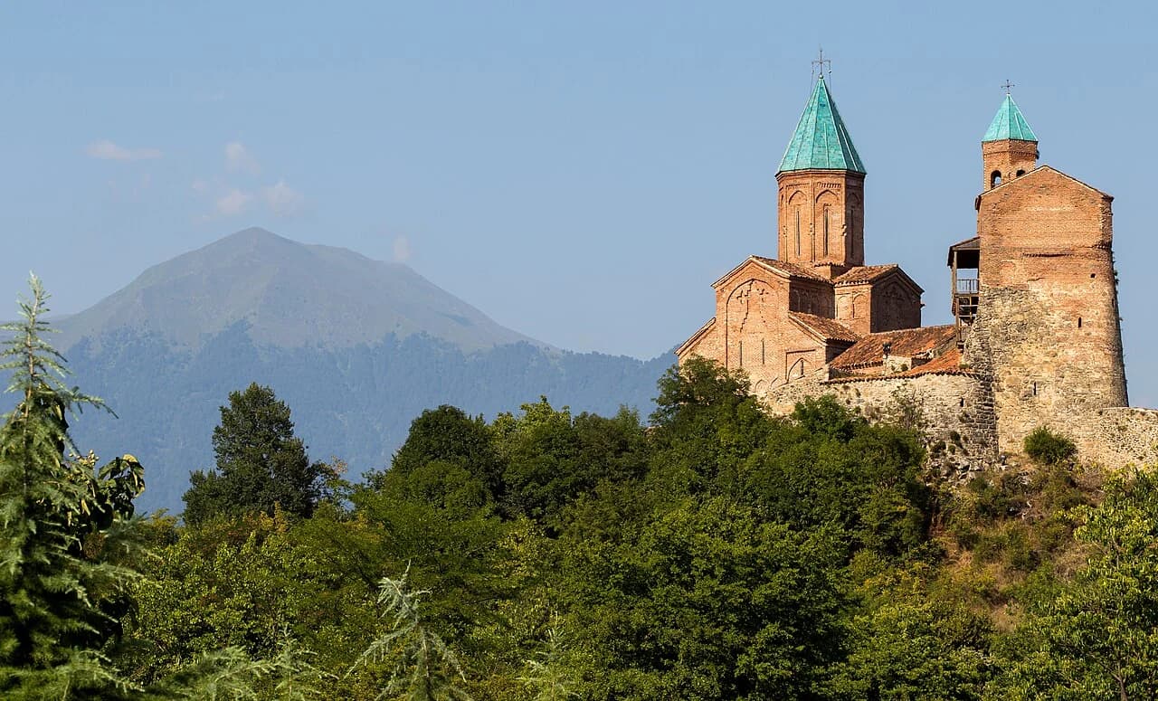 Die historischen Türme von Gremi über grünen Hügeln, dahinter die Berge Kachetiens.